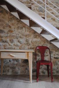 a red chair sitting next to a desk under a stairs at LA OTRA KASA in Alameda del Valle