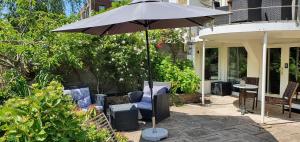 an umbrella on a patio with chairs and a table at Verborgen Parel aan de Rotte in Rotterdam