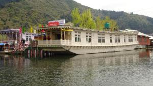 Un grand bateau blanc est amarré dans l'eau. dans l'établissement Shiraz Deluxe Houseboat, à Srinagar