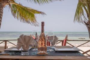 einen Tisch mit einer Flasche und Gläsern am Strand in der Unterkunft Mamamapambo Boutique Hotel in Jambiani