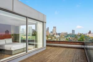 balcón con cama y vistas a la ciudad en Roomzzz London Stratford, en Londres