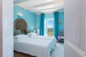 1 dormitorio azul con 2 camas y ventana en Korakiana Cottage, en Áno Korakiána