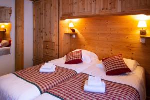 two beds in a hotel room with two towels at Chalet Hotel La Tarine in Peisey-Nancroix