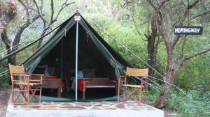 namiot z 2 krzesłami, stołem i znakiem ulicznym w obiekcie Maasai Simba Camp w mieście Amboseli