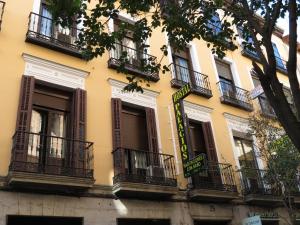 un edificio amarillo con ventanas y balcones en Hostal Palacios Fuencarral, en Madrid