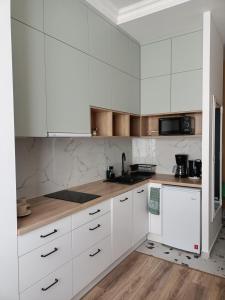 Biała kuchnia z białymi szafkami i drewnianą podłogą w obiekcie przytulnie w Łodzi w Łodzi