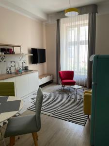 a living room with a table and a red chair at Cracow Rentals Zacisze in Krakow