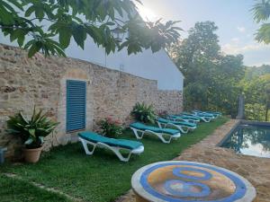 uma fila de espreguiçadeiras sentadas ao lado de uma piscina em Casa Rural Castillo JABUGO em Jabugo