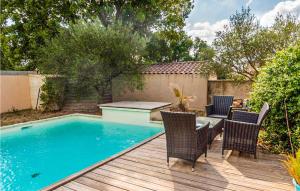 einen Pool mit Stühlen und einem Tisch auf einer Holzterrasse in der Unterkunft Amazing Home In Saint-quentin-la-poter With Outdoor Swimming Pool in Saint-Quentin-la-Poterie