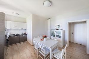 uma cozinha branca com uma mesa e cadeiras brancas em Casa Alba con giardino e patio by Wonderful Italy em Lonato