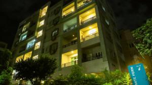 un immeuble d'appartements avec ses lumières allumées la nuit dans l'établissement White Fern Stays Serviced Apartments - Gachibowli, à Hyderabad