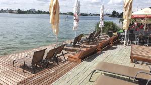 a row of chairs and umbrellas on a dock with the water at Apartmánový Garni Hotel Relax in Senec