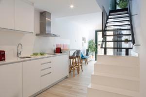 a kitchen with white cabinets and a staircase at Urban Suites Sitges Apartments in Sitges