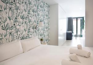 una camera da letto con un letto bianco e carta da parati floreale di Urban Suites Sitges Apartments a Sitges