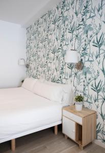 a bedroom with a white bed and a blue and white wallpaper at Urban Suites Sitges Apartments in Sitges