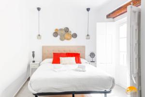 een witte slaapkamer met een groot wit bed met rode kussens bij Casa Rehala by Cadiz Time in Cádiz