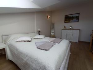 a bedroom with a white bed with towels on it at kotedžas Akvilė in Nida