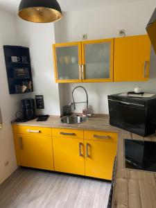 a kitchen with yellow cabinets and a sink at City Apartment #2 bei der Porzellan Manufaktur in Meißen