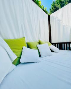 a white bed with green and white pillows on it at Hotel La Pigna in Marina di Pietrasanta