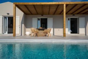 un patio con mesa y sillas junto a una piscina en Summer Breeze Villa, en Tzamarelláta