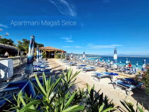 a beach with a bunch of chairs and umbrellas at Apartmani Magaš in Selce