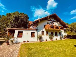 ein Haus mit Balkon und Rasen in der Unterkunft Sommer Panzió in Balatonföldvár