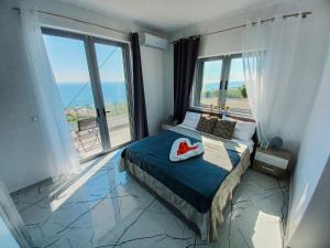a bedroom with a bed with a large window at Ionian Pearl in Dhërmi