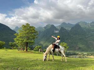 a woman is riding a horse in a field at H'mong Village Resort in Ha Giang