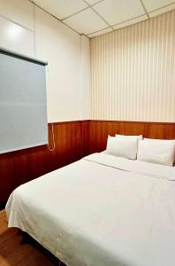a bedroom with a white bed and a projection screen at Ying Lun Hotel in Taitung City