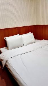 a large white bed with white sheets and pillows at Ying Lun Hotel in Taitung City