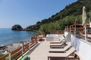 a balcony with chairs and a pool and the ocean at Villa Renata & Villa Filippos with private Plunge Pool by Konnect in Agios Gordios