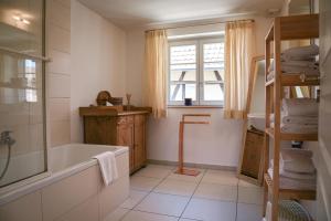 een badkamer met een bad, een wastafel en een raam bij Le Hameau d'Eguisheim - Chambres d'hôtes & Gîtes in Eguisheim