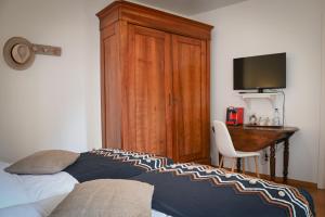 Dormitorio con cama, escritorio y TV en Le Hameau d'Eguisheim - Chambres d'hôtes & Gîtes en Eguisheim
