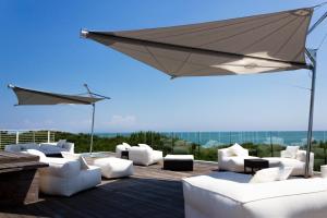 eine Terrasse mit weißen Möbeln und einem Sonnenschirm in der Unterkunft Hotel Mediterraneo Suite&Residence in Lido di Jesolo