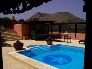 einen blauen Pool mit einem Pavillon und einem Tisch in der Unterkunft Casa El Morro in Uga