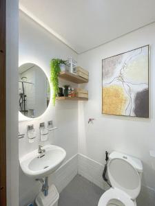 La salle de bains est pourvue de toilettes blanches et d'un lavabo. dans l'établissement Spring Residences 1 Bedroom Deluxe Near Airport, à Manille