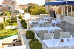 an outdoor restaurant with white tables and chairs at Hotel Mediteran in Zadar
