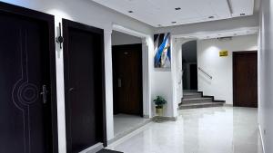 un pasillo con puertas negras y escaleras en un edificio en اجواء المساء للوحدات السكنيه المفروشه, en Riad