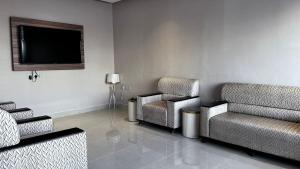 Habitación con 2 sillas y TV de pantalla plana. en اجواء المساء للوحدات السكنيه المفروشه, en Riad