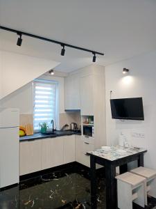 uma cozinha com armários brancos e uma mesa em Family Apartments Dorobok em Lviv