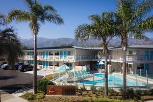 a view of a hotel with a pool and palm trees at Motel 6-Santa Barbara, CA - Beach in Santa Barbara