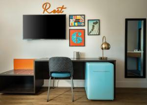 a desk with a chair and a tv on a wall at Motel 6-Santa Barbara, CA - Beach in Santa Barbara