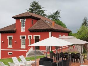a red building with chairs and umbrellas in front of it at Villa Burión in Llanera