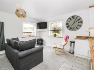 a living room with a couch and a clock on the wall at Swaledale Watch House Annexe in Wigton