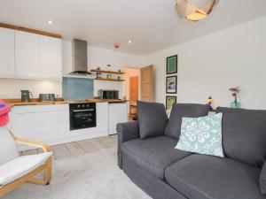 a living room with a couch and a kitchen at Swaledale Watch House Annexe in Wigton