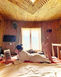 Una donna sdraiata su un letto che legge un libro di H'mong Village Resort a Ha Giang