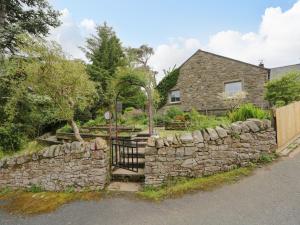 a stone house with a gate and a stone wall at Swaledale Watch House Annexe in Wigton