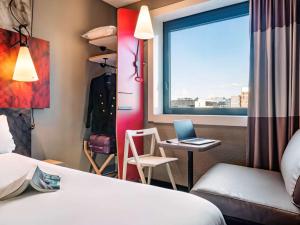a hotel room with a bed and a desk with a laptop at Ibis Marne la Vallée Noisy in Noisy-le-Grand