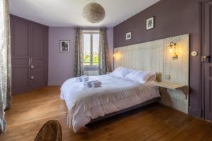 - une chambre avec un grand lit aux murs violets dans l'établissement Maison du Grichet - Piscine privée, à Condom