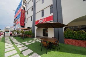 a table and chairs with an umbrella in front of a building at The Point Boutique Hotel in Johor Bahru